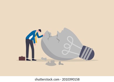 Uninspired or motivation after business failure, burnout or exhausted from crisis, no new idea or inspiration concept, depressed business man sadly standing with fail old broken lightbulb idea.