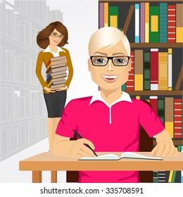 university male student with open book styding in the college library and young happy librarian with glasses holding stack of books cstanding behind him