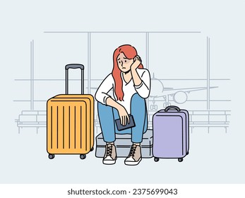 Upset woman airport passenger sits among tourist suitcases and waits for plane that is late due to bad weather. Concept of flight cancellation causing inconvenience to airport passengers