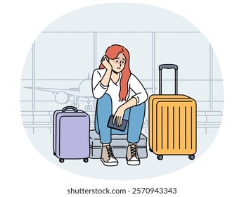 Upset woman airport passenger sits among tourist suitcases and waits for plane that is late due to bad weather. Concept of flight cancellation causing inconvenience to airport passengers