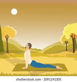 Upward Facing Dog or Urdha Mukha Shvanasana posture perfomed by handsome fit man outside in the field with mountines view in the mid day. Man is doing yoga at nature with autumn colors. 
