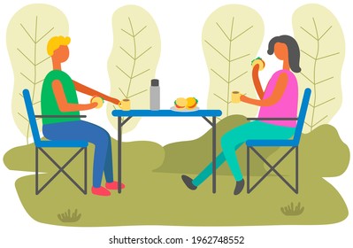 Urban park visitors drink coffee at table. Young man and woman are sitting in outdoor cafe and drinking hot beverage. People in relationship communicate on date together during cold weather