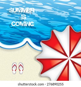 Vacation at the seaside with a red beach umbrella from above and flip-flop on the sand lapped by a blue ocean