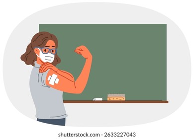 Vaccinated female teacher demonstrates patch at injection site on arm, standing near school board. Vaccinated girl teacher recommends taking preventive measures to protect against virus