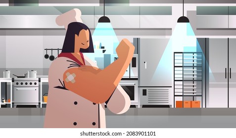 vaccinated woman chef in uniform after vaccine injection successful covid-19 vaccination concept kitchen interior