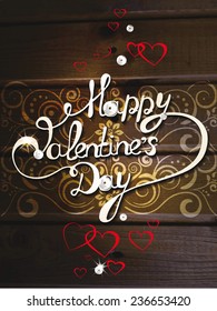 Valentine's day composition with hand drawn Happy Valentines Day on the wooden background