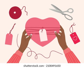 Valentine's day concept. Black female hands hold gift box wrapped into kraft paper. Top view table with romantic eco-friendly packaging, hearts, ribbon, scissors. Hand drawn vector illustration