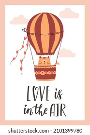 Valentine's Day greeting card with a cute cat flying on a hot air balloon. The handwritten phrase Love is in the air. Hand lettering. Cartoon vector illustration isolated on a white background.