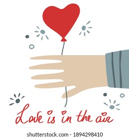 Valentine's Day greeting card. Hand lettering love in the air. Hand holding a balloon.