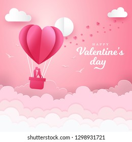 Valentine's Day greeting card with romantic couple kissing and standing inside a basket of an air balloon. paper cut style vector illustration
