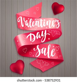 Valentine's Day Sale. Holiday card with calligraphy, red ribbon and decorative elements.  Handwritten modern lettering with hearts on wooden background.
