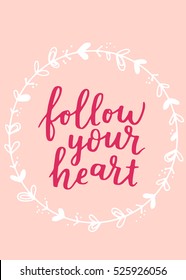 Valentine's Day vector greeting card. Hand written lettering with quote follow your heart and floral wreath on rose pink isolated background. Cute label design.