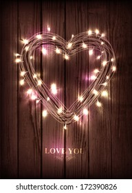 Valentine's heart-shaped wreath made of led lights on the wooden background 