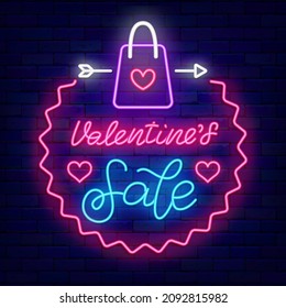 Valentines Sale letras de neón en círculo. Publicidad ligera con bolsa de compra. Afiche de efecto luminoso exterior. Diseño romántico de vacaciones en la pared de ladrillos. Trazo editable. Ilustración de material vectorial