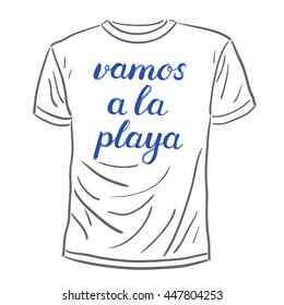 Vamos a la playa. Let s go to the beach in Spanish. Brush hand lettering on a sample t-shirt. Great for beach tote bags, swimwear, holiday clothes, and more.