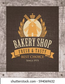 Vector banner for a bakery shop with a picture of the windmill and ears of wheat on the background of sacking and in wooden frame.