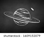 Vector black and white chalk drawn illustration of Saturn planet with piece of chalk on black chalkboard background.