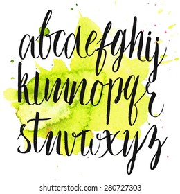 Vector brush alphabet at green watercolor splash. Artistic hand drawn letters.