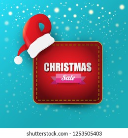 vector Christmas sales paper banner or tag label with red santa hat on snowy azure background with falling snowflakes. Red winter Christmas sale poster design template or background