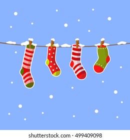 Vector christmas socks hanging on a rope with snowflakes around. Cute winter illustration. Cartoon x-mas picture.