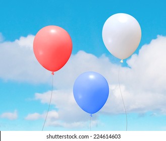 Vector colorful helium balloons over a blue sky with clouds