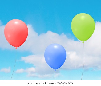 Vector colorful helium balloons over a blue sky with clouds