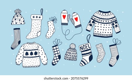 Vector doodle set with warm clothes on blue background with white polka dots. Clothes elements for winter season - socks, Christmas stocking, mittens, sweaters, hats.
