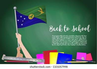 Vector flag of Christmas Island on Black chalkboard background. Education Background with Hands Holding Up of Christmas Island flag. Back to school with pencils, books, school items learning