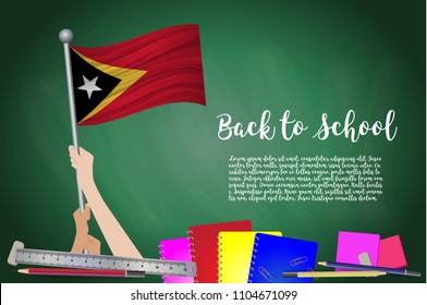 Vector flag of East Timor on Black chalkboard background. Education Background with Hands Holding Up of East Timor flag. Back to school with pencils, books, school items learning and childhood concept