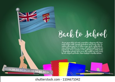 Vector flag of Fiji on Black chalkboard background. Education Background with Hands Holding Up of Fiji flag. Back to school with pencils, books, school items learning and childhood concept.