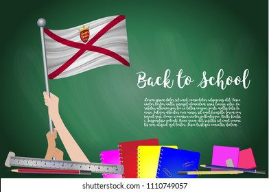 Vector flag of Jersey on Black chalkboard background. Education Background with Hands Holding Up of Jersey flag. Back to school with pencils, books, school items learning and childhood concept.