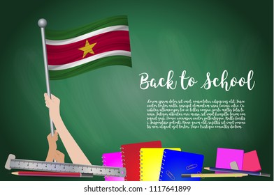 Vector flag of Suriname on Black chalkboard background. Education Background with Hands Holding Up of Suriname flag. Back to school with pencils, books, school items learning and childhood concept.