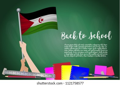Vector flag of Western Sahara on Black chalkboard background. Education Background with Hands Holding Up of Western Sahara flag. Back to school with pencils, books, school items learning and childhood