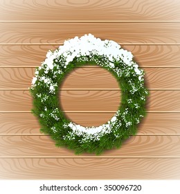 Vector Green Christmas wreath with snow on wooden background