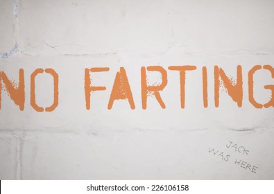 Vector grungy distressed painted graffiti style announce on white brick wall background - No farting