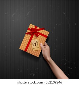 Vector hands holding gift box with red ribbon bow with deer label 