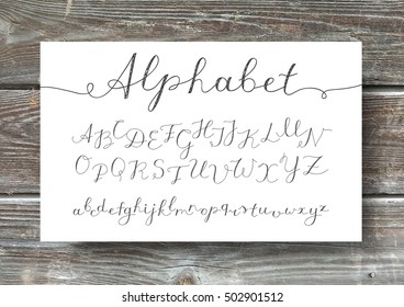 vector handwritten lettering alphabet, calligraphic font on old wood texture