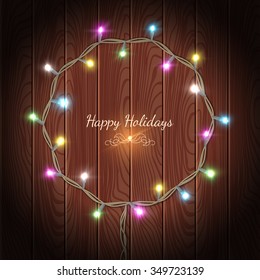 Vector Happy Holidays greeting card with Glowing Lights Wreath on wooden background
