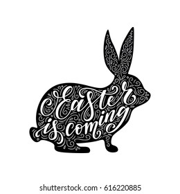 Vector illustration of  calligraphic inscription in a bunny shape. Easter is coming hand drawn phrase. Easter design element.