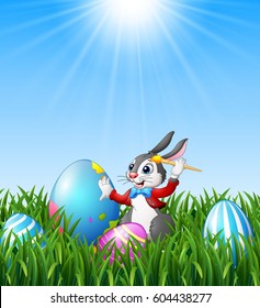 Vector illustration of Cartoon easter bunny painting easter eggs in the grass