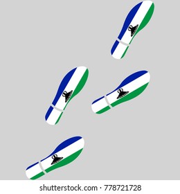 Vector illustration of chain of trails of shoes isolated on grey background, painted in the colors of national flag of Lesotho