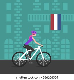 Vector illustration of cyclist girl on bike that rides through the city; biker and bicycling; sport and exercise. Flag of Netherlands on the balcony. Healthy lifestyle in Netherlands.