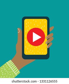 Vector illustration of the hand holding smartphone or mobile phone with with video player on the screen. Movie app concept in the flat design.