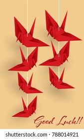 Vector illustration of hanging origami paper cranes in red color and "Good Luck!" text on yellow background. Flat design style.