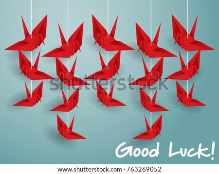 Vector illustration of hanging origami paper cranes in red color and "Good Luck!" text on blue background. Flat design style.