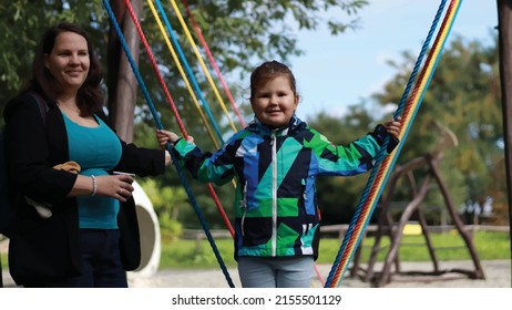 Vector illustration of mom with daughter. Child standing on rocking outdoor balance beam hanging on colorful ropes. Mom with daughter. People. Outdoor environment. Portrait, people.