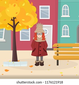 Vector illustration of pretty cartoon girl in warm clothes in autumn city. Vector city street with yellow tree and bench. Red haired girl with big eyes and glasses stands smiling. EPS 10