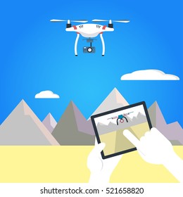 Vector illustration of quadrocopter and operator's hands holding remote control. Air RC drone hovering above the mountains and  desert. Flat design. Isolated background.