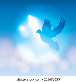 A vector illustration of a silhouetted dove flying against a blue background with soft bokeh lighting. Vector EPS 10 available. EPS file contains transparencies.