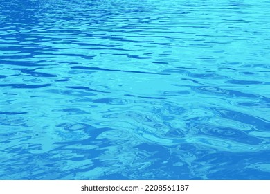 Vector illustration of water ripple texture background. Wavy water surface during sunset, golden light reflecting in the water.